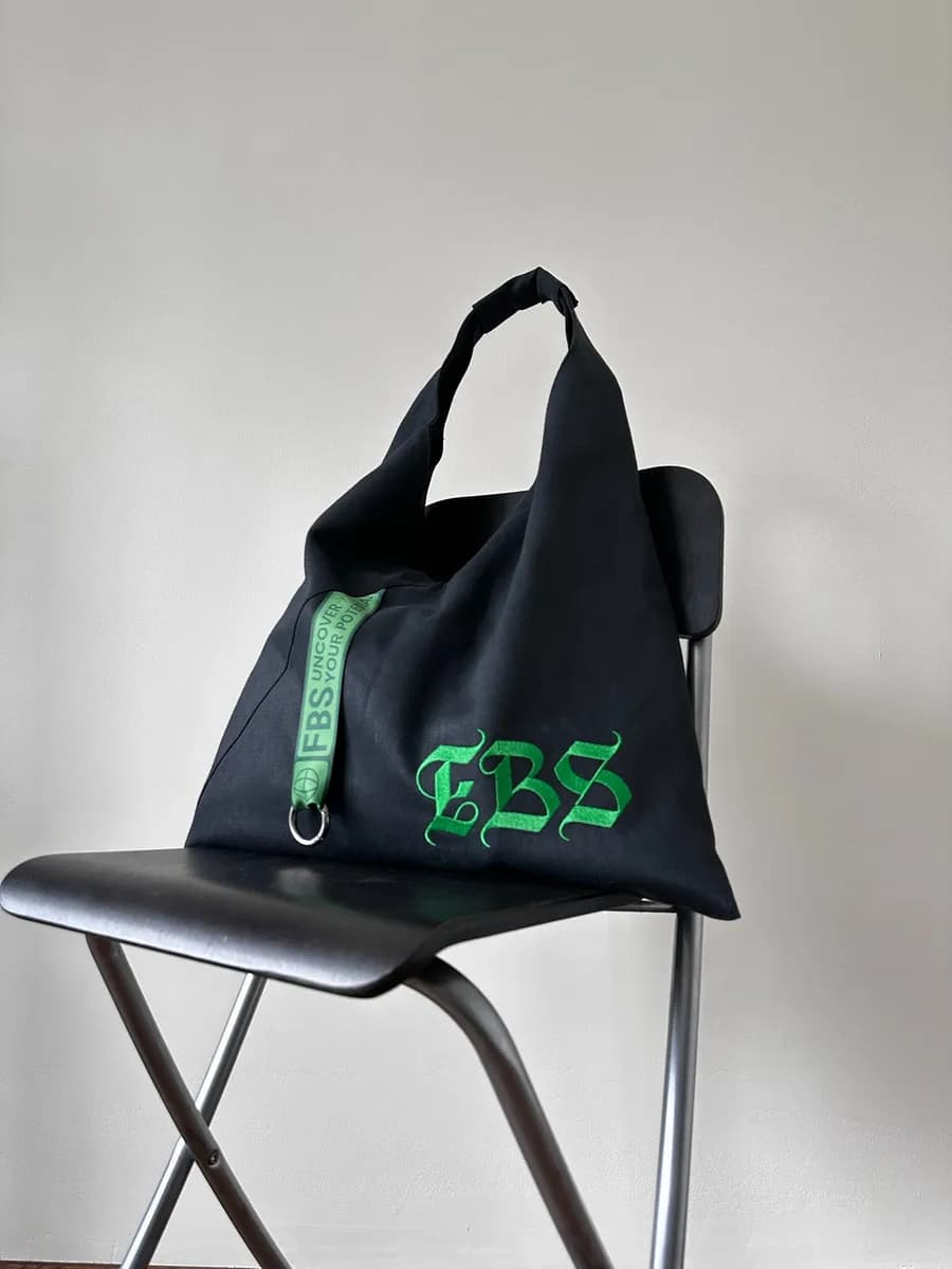 Black tote bag with a green embroidered logo