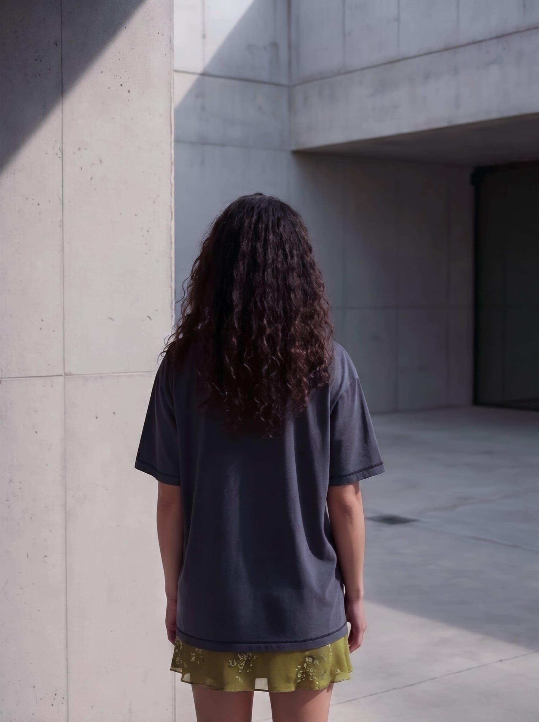 365.APParel Basic T-shirt Graphite — woman, full body back view, concrete architecture, outdoor