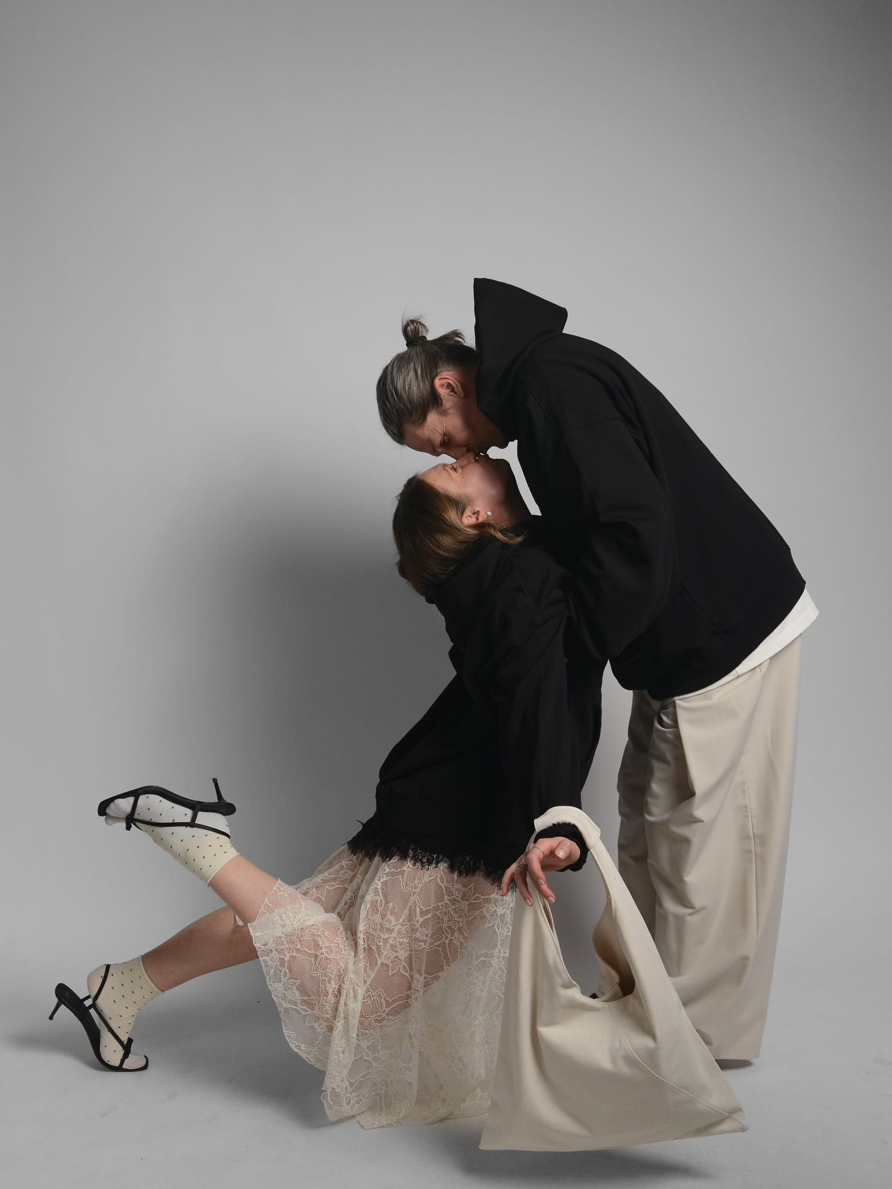 365.APParel Oversize Hoodie Black — couple in matching hoodies, romantic dip, kissing, tote bag, studio