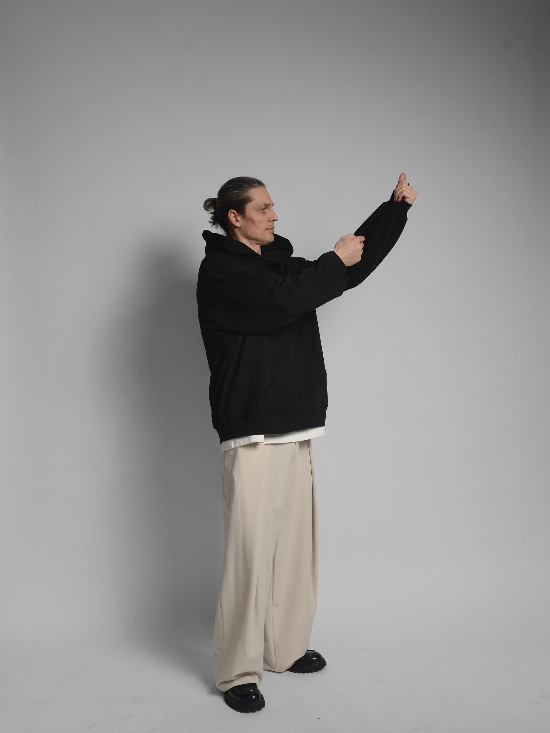 365.APParel Oversize Hoodie Black — man, full body front, glasses, hood visible, gallery wall, indoor