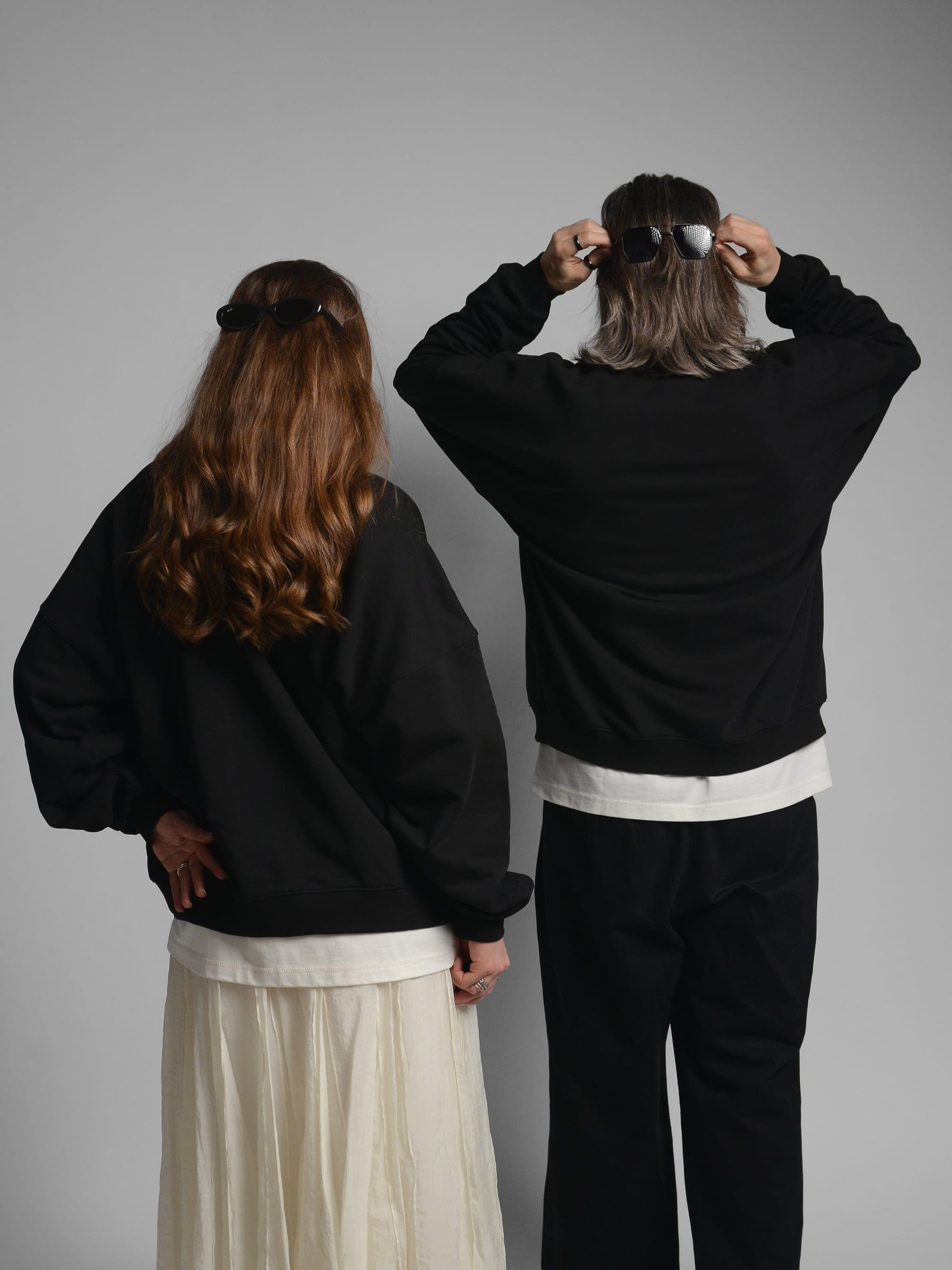 365.APParel Oversize Sweatshirt Black — couple, cropped back view, man adjusting sunglasses on head, woman hand on hip, studio