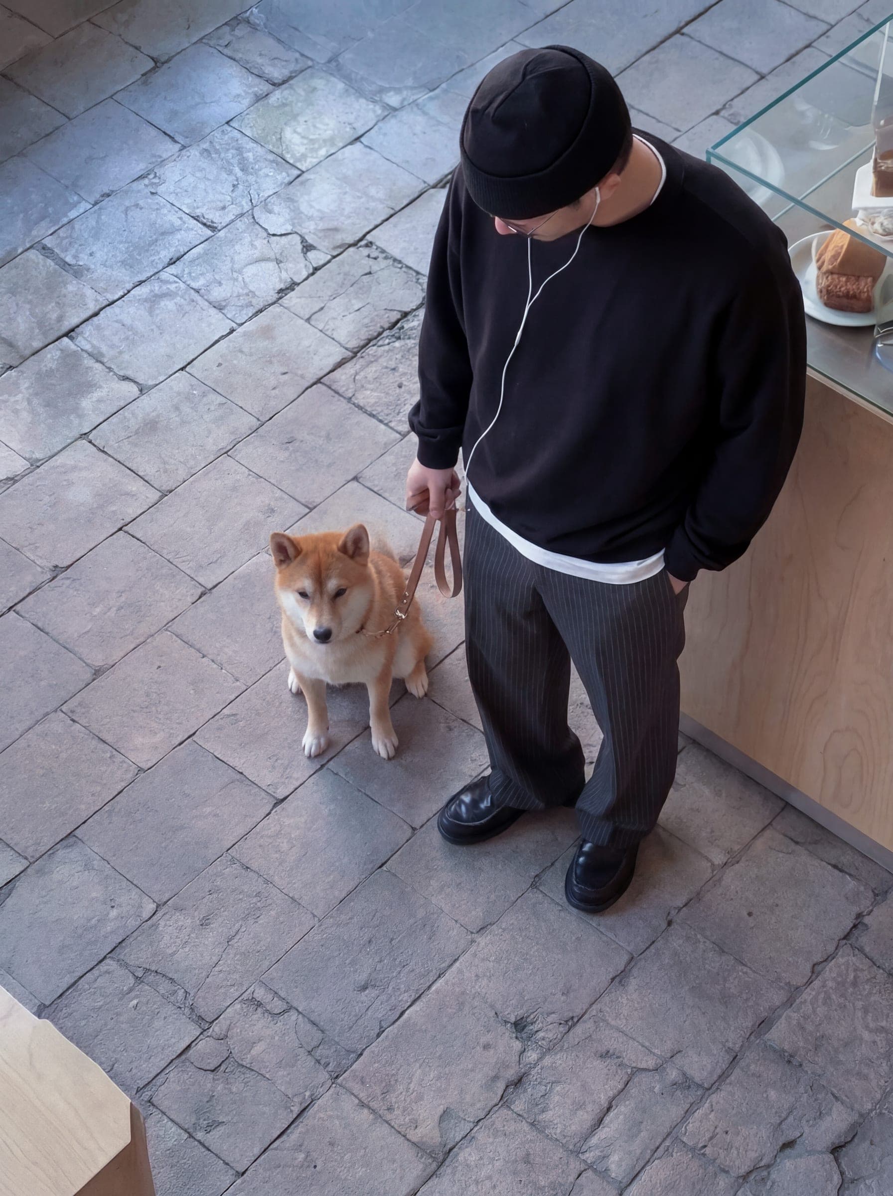 365.APParel Oversize Sweatshirt Black — man, overhead view, Shiba Inu on leash, earphones, beanie, wine bar, indoor