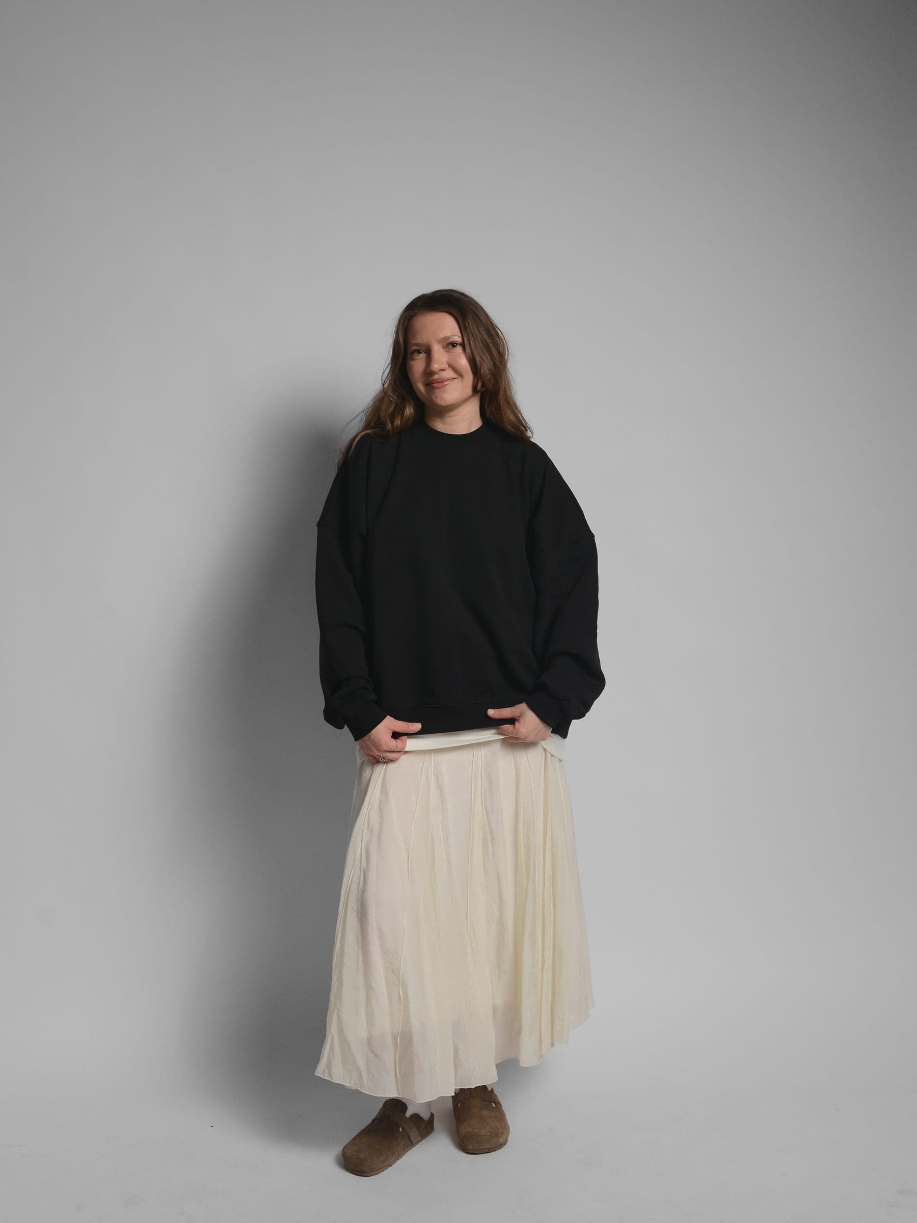 365.APParel Oversize Sweatshirt Black — woman, full body front, smiling, pleated maxi skirt, studio