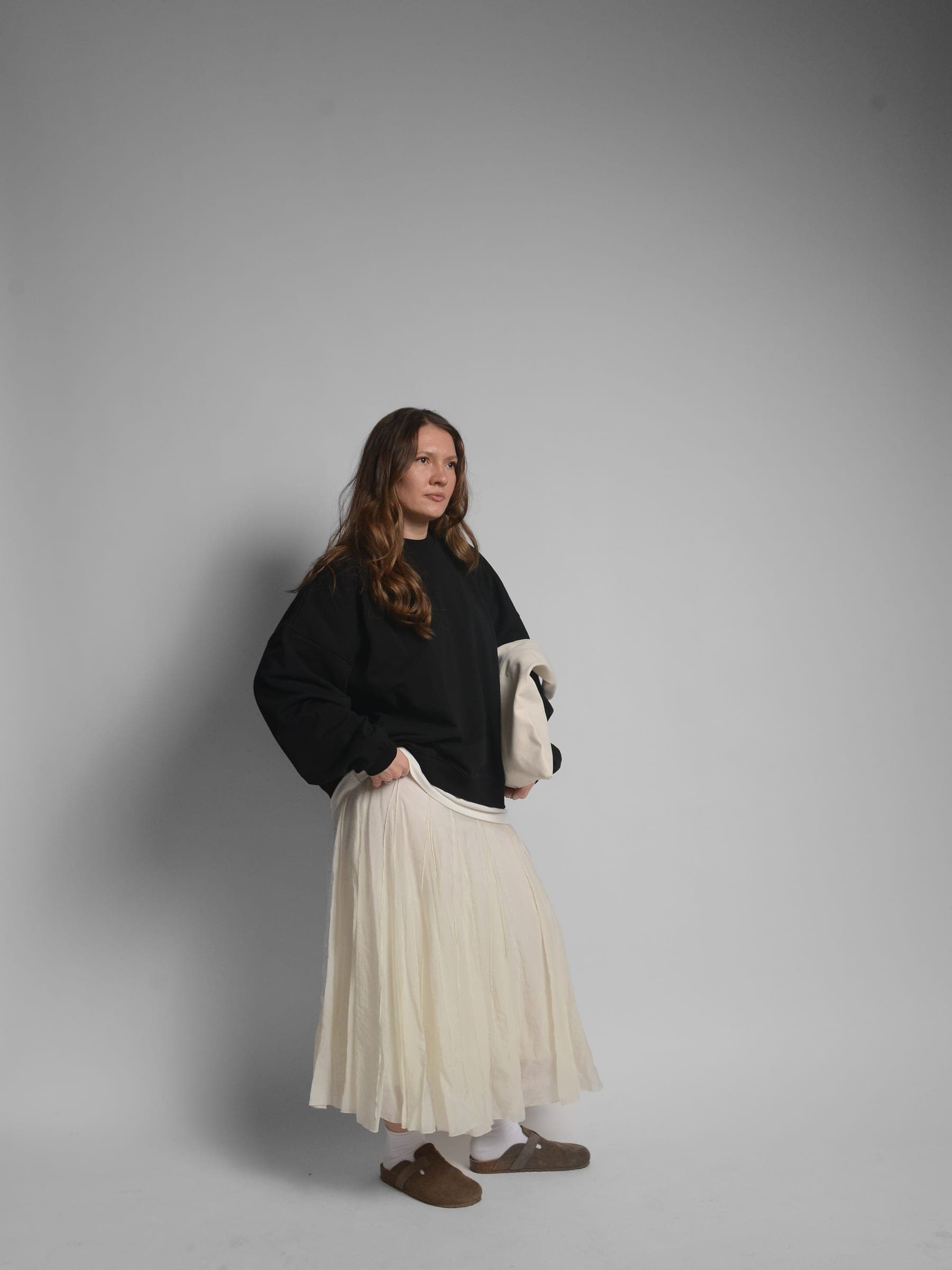 365.APParel Oversize Sweatshirt Black — woman, full body three-quarter view, tote bag, pleated maxi skirt, studio