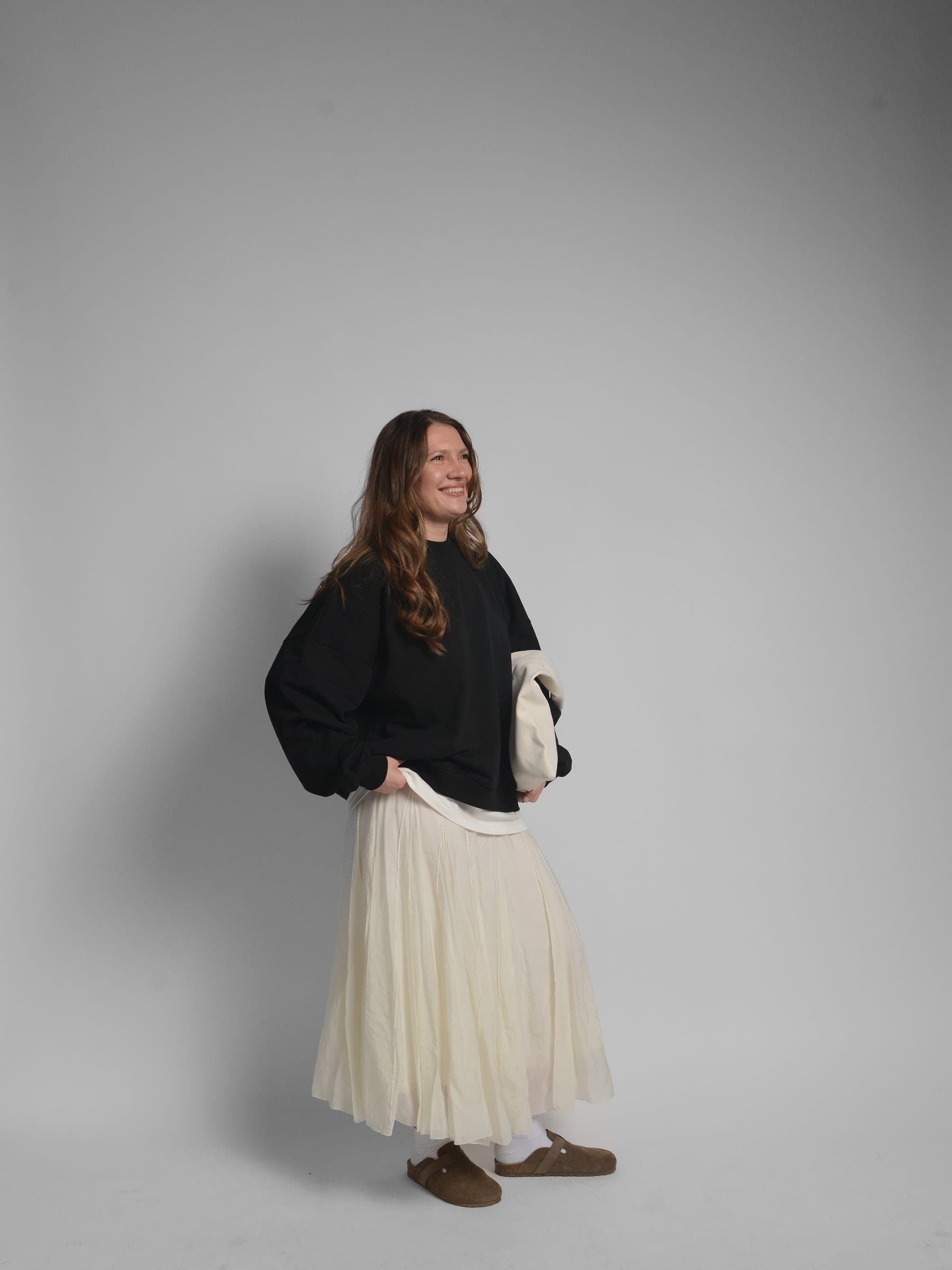 365.APParel Oversize Sweatshirt Black — woman, full body side view, smiling, tote bag, pleated maxi skirt, studio