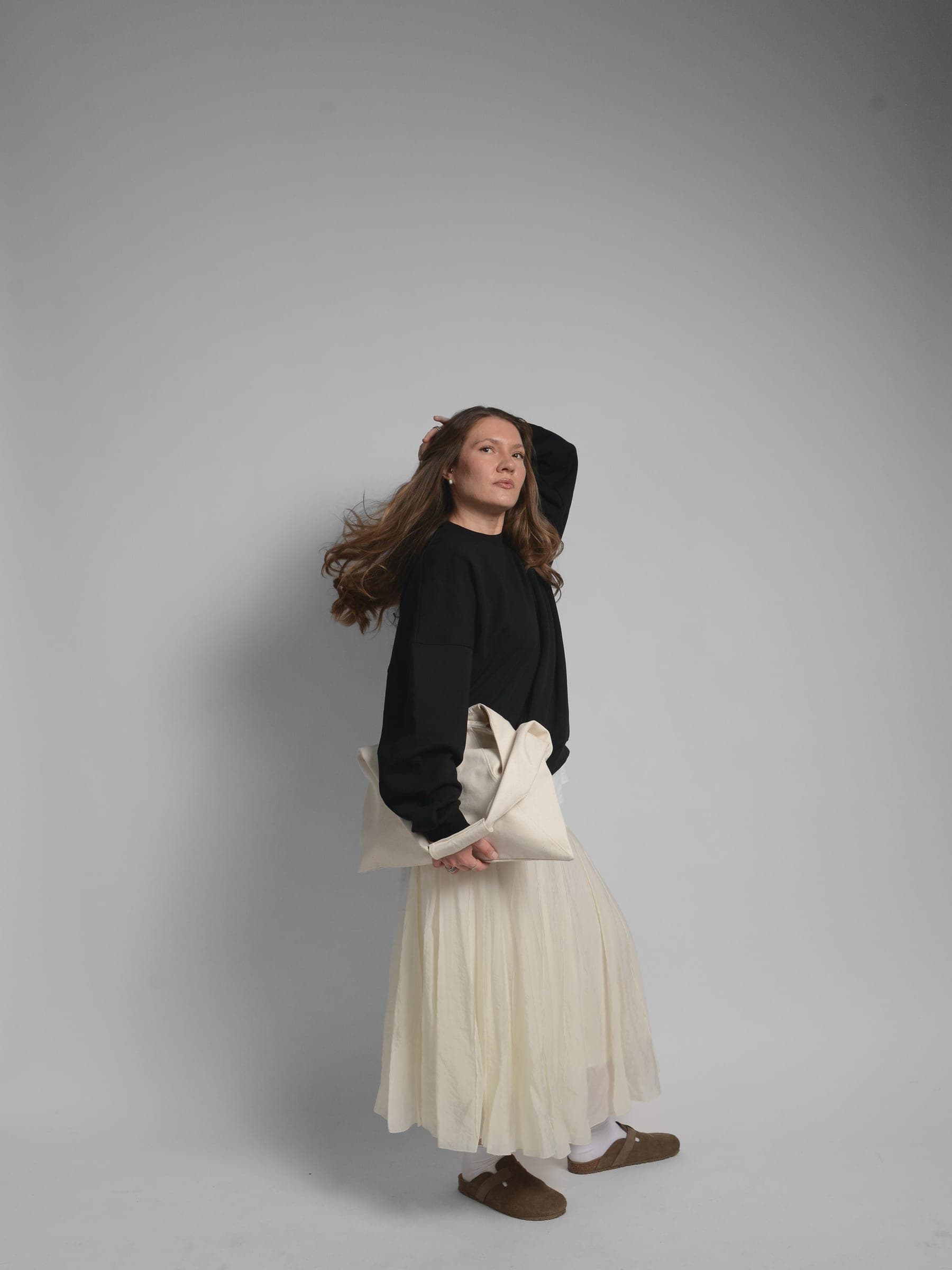 365.APParel Oversize Sweatshirt Black — woman, full body side view, head tilted back, hand in hair, tote bag, studio