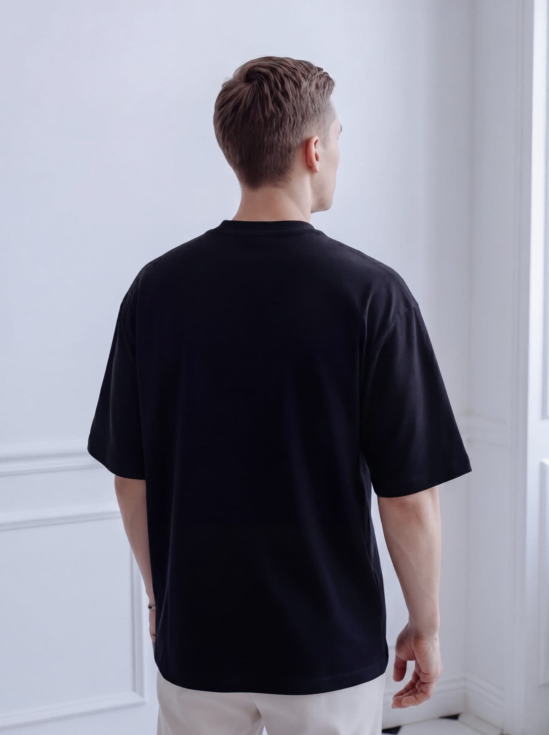 365.APParel Oversize T-shirt Black — man, portrait crop, three-quarter front, direct gaze, indoor editorial