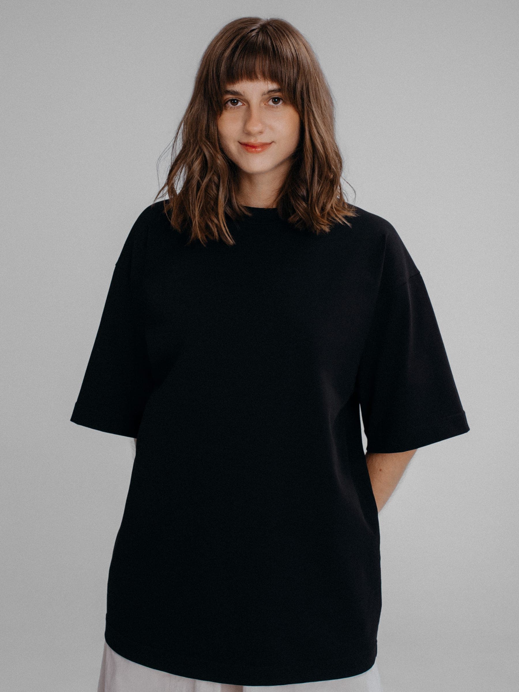 365.APParel Oversize T-shirt Black — woman, cropped front view, slight smile, studio
